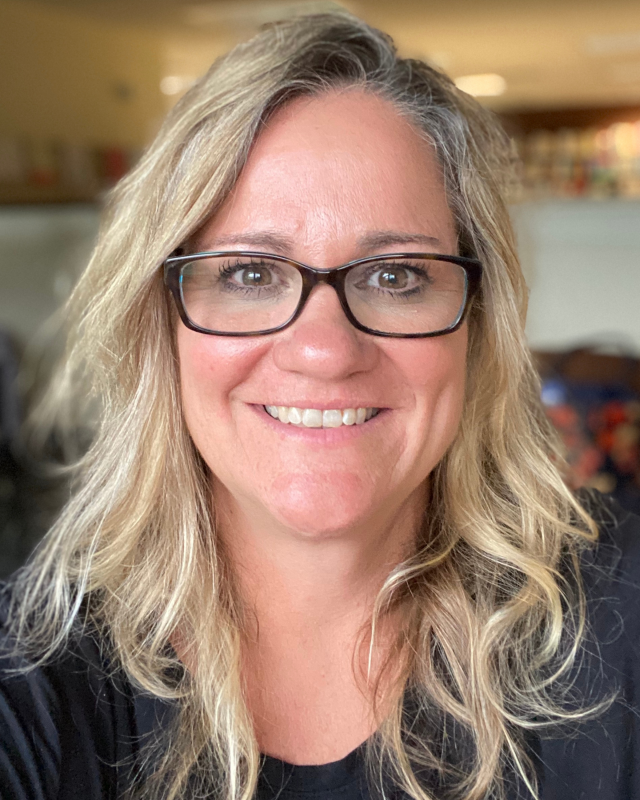 woman with blonde hair and glasses smiling