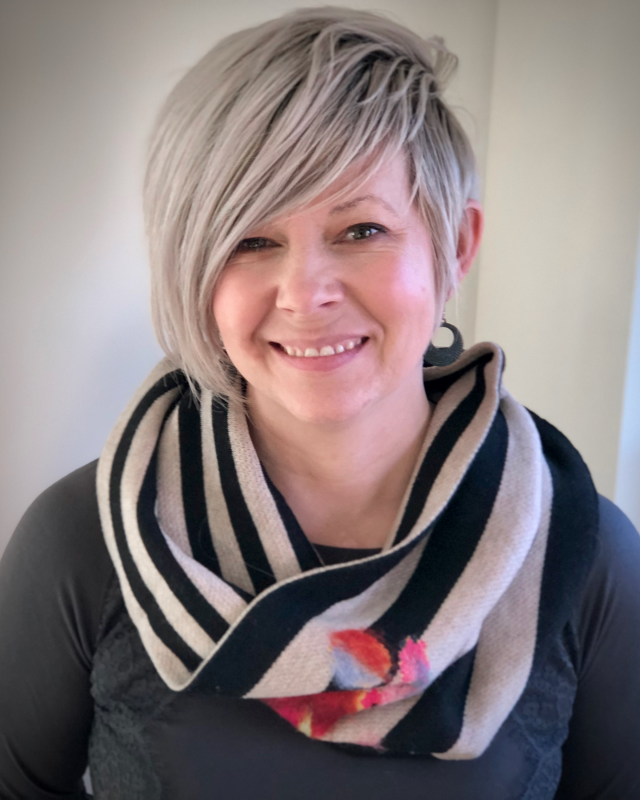 woman with short blonde hair and scarf smiling