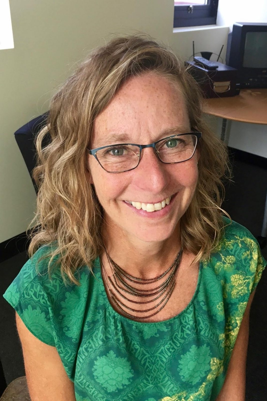 Woman in green shirt with glasses smiling